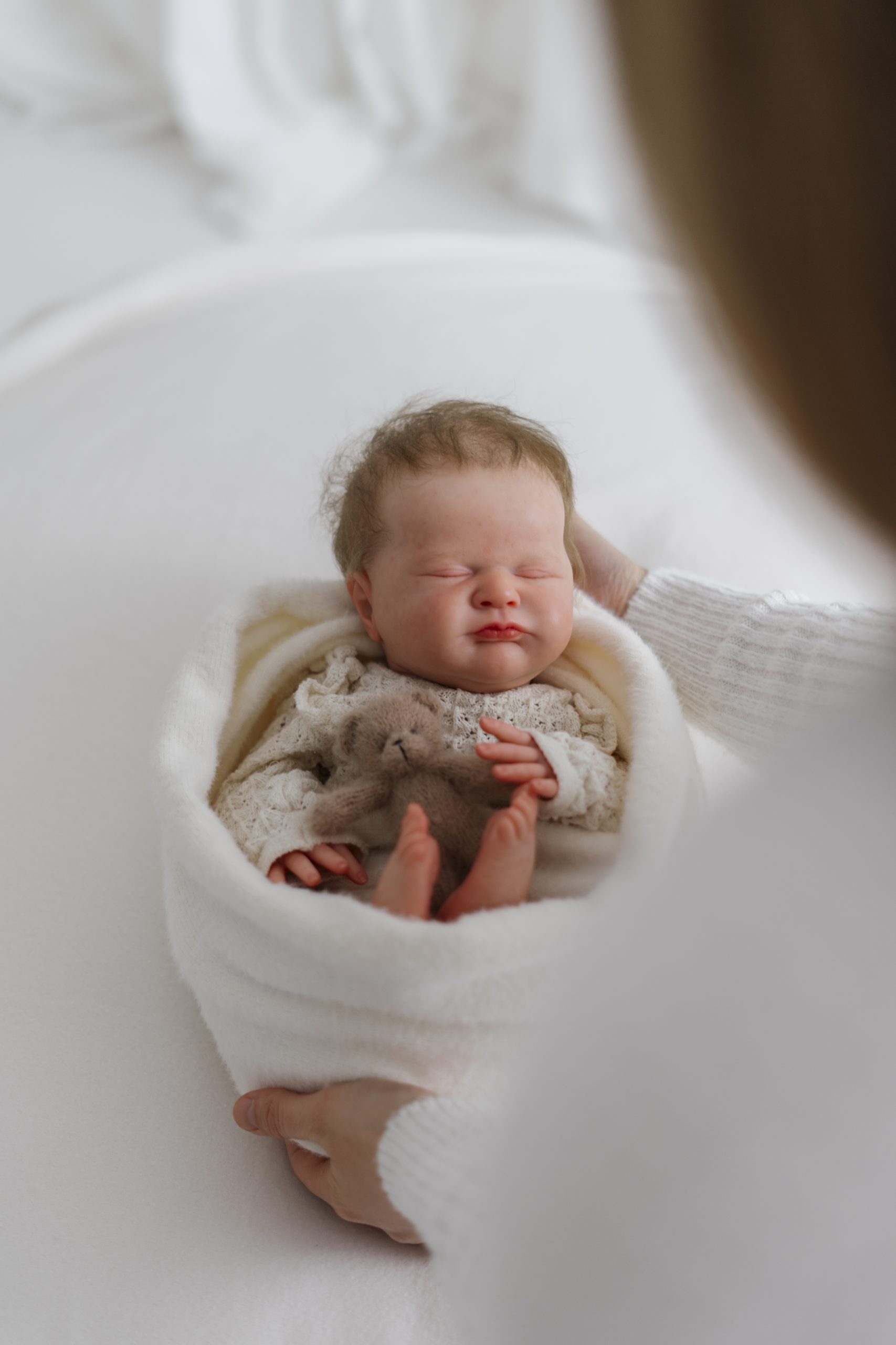 Frau hält ein Baby in ihren Armen und streichelt es ganz sanft. Fotograf / Fotografin in Münchberg, Landkreis Hof, Oberfranken